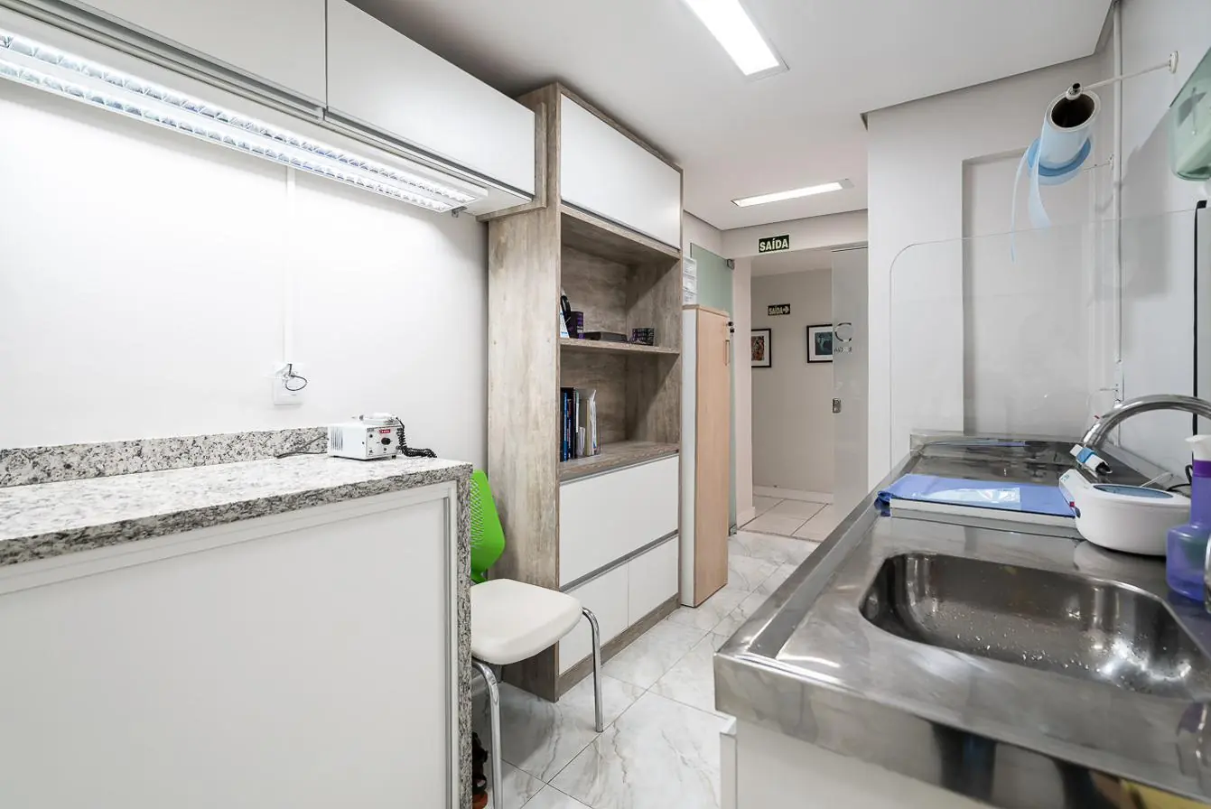 Área de esterilização com bancada de aço inox e armários brancos